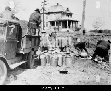Striking farmers dump milk cans from a truck they have stopped to prevent delivery to market during the Great Depression. Milk strikes failed because most farmers were owner-operators and would not voluntarily destroy their produce. Ca. 1930-36. Stock Photo