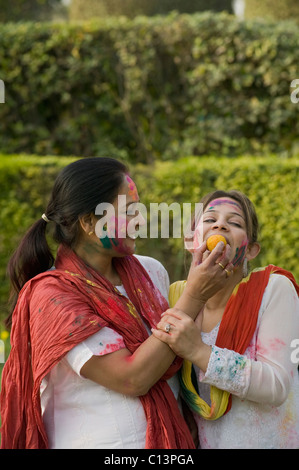 Woman feeding sweet to her daughter on Holi Stock Photo