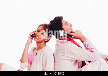 Couple talking on mobile phones on Holi Stock Photo