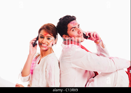 Couple talking on mobile phones on Holi Stock Photo