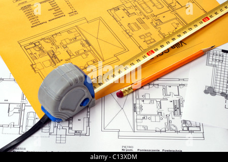 A measuring tape and a pencil on a floor plan blue print. Print on yellow and white paper sheet Stock Photo