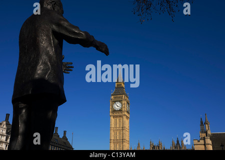 Reaching hands of ex-South African President Nelson Mandela's statue seemingly grasp Elizabeth Tower in Parliament Square. Stock Photo