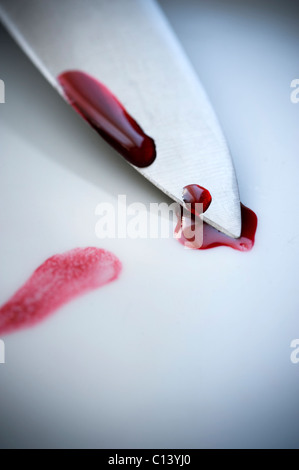 blade of a knife on a white surface with drops of blood