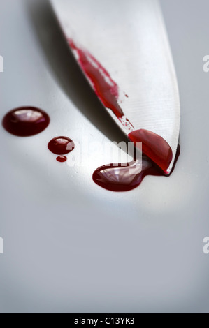 blade of a knife on a white surface with drops of blood