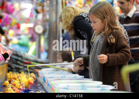 Girl playing hook the duck at funfair Stock Photo