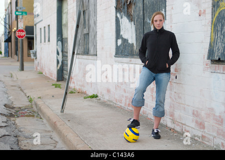 Blond soccer girl on the streets in an urban environment. Stock Photo