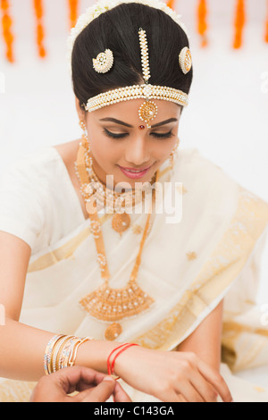 Close-up of a person's hands putting kankanam on a bride's hand Stock Photo