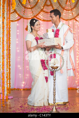 Newlywed couple holding presents and smiling Stock Photo