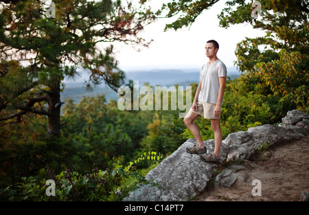 Young man stops to look out at an overlook while hiking at Oak Mountain State Park in Birmingham, Alabama. Stock Photo