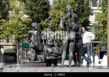 A tourist poses on The Bathing Ladies sculpture, part of main fountain in the Zand Square, Bruges (Brugge), Belgium Stock Photo