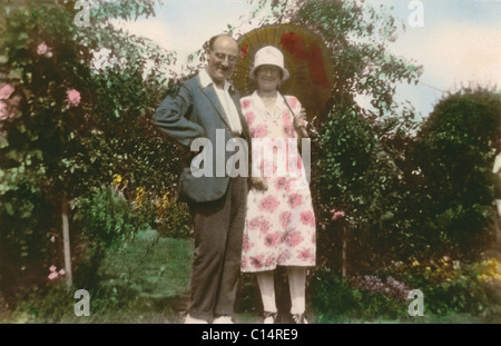 Tinted photograph of couple in sunny garden, the lady wears a cloche hat ,circa 1928, twenties 20's U.K. Stock Photo