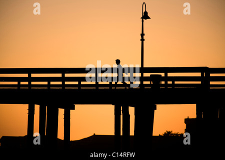 A silhouetted woman walks along the Ventura Pier in Ventura, California. Stock Photo