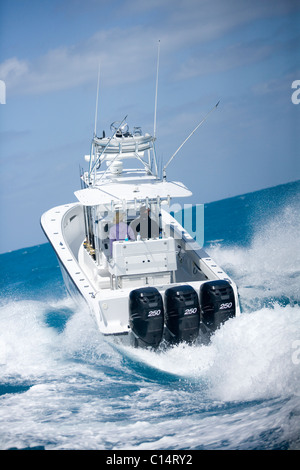 A fishing boat speeds through the blue surf spraying white water. Stock Photo