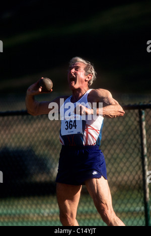 Elderly male track and field athlete throwing the shot. Stock Photo