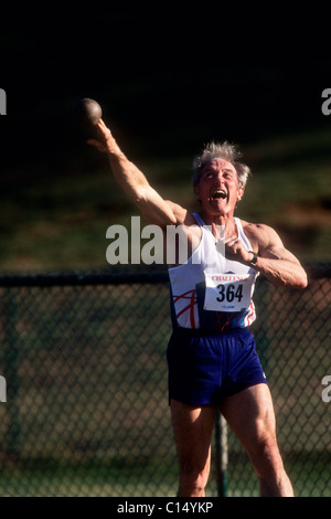 Elderly male track and field athlete throwing the shot. Stock Photo