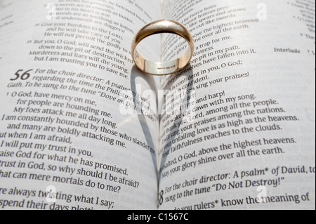 A wedding ring casting a shadow on the open pages of an open religious book Stock Photo