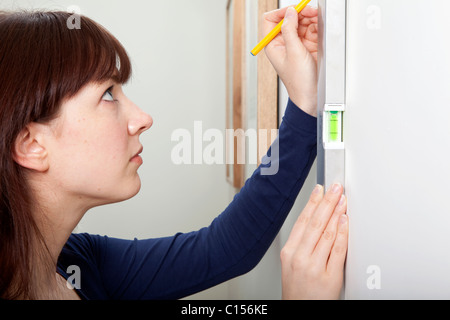 A woman using a spirit level to complete a DIY task. Stock Photo