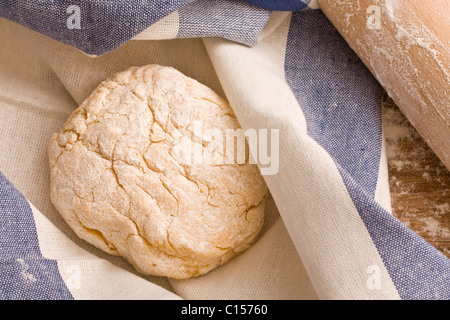 Fresh dough in towel with rolling pin Stock Photo