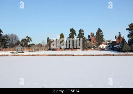 Capesthorne Hall, England. Picturesque winter view of frosty trees with a frozen lake and Capesthorne Hall in the background. Stock Photo