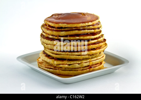 Pancakes with syrup poured over at dish on white background Stock Photo