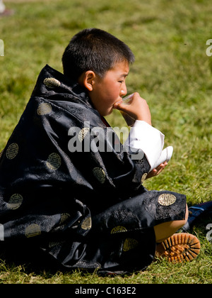 Young boy in a traditional gho drinking Stock Photo