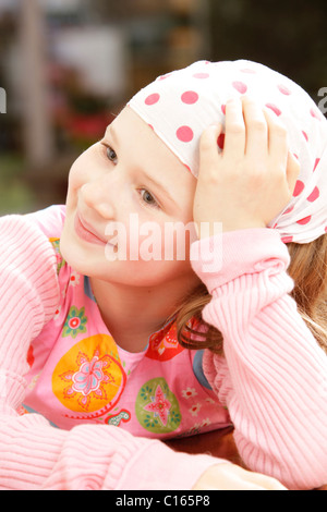 Girl, 8 years old, wearing a headscarf and smiling while looking to the side Stock Photo