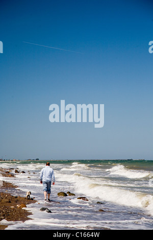 Man walking with a dog along a beach on the Baltic Sea Stock Photo