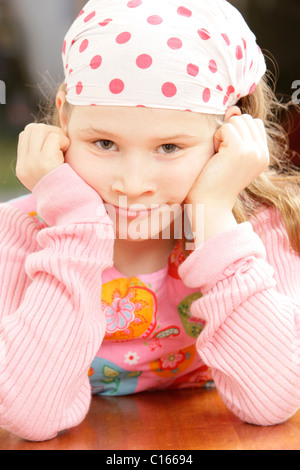 Girl, 8 years old, wearing a headscarf supporting her head in her hands Stock Photo