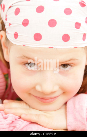 Girl, 8 years old, wearing a headscarf, supporting her head in her hands Stock Photo