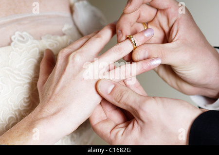 Groom placing the wedding ring on the bride's finger Stock Photo