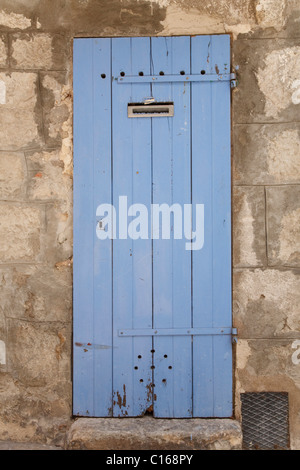 Traditional wooden door in faded blue paint, set in an ancient stone wall Stock Photo