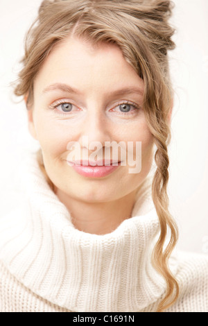 Blonde woman with curly hair wearing a white turtle neck collar Stock Photo