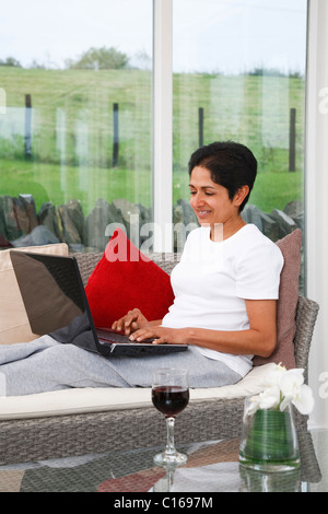 Young Indian Asian woman relaxes using the internet at home Stock Photo