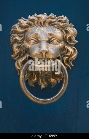 Traditional brass door knocker in the shape of a lion's head against a blue painted door Stock Photo