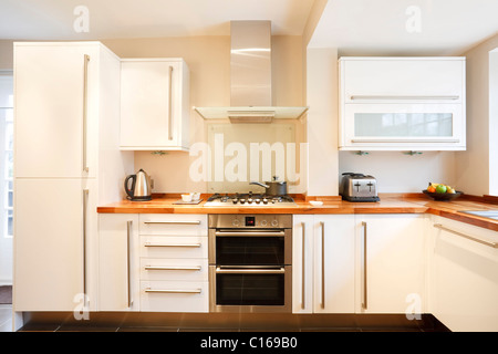 Modern white kitchen with wooden worktops and stainless steel appliances Stock Photo