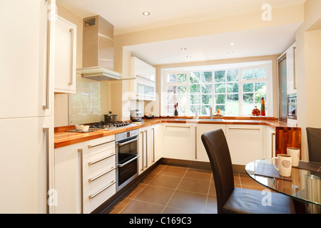 Contemporary designer kitchen and breakfast area with modern white units and stainless steel appliances Stock Photo