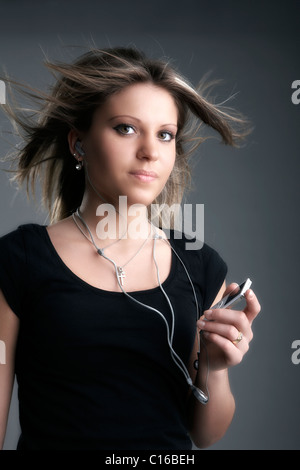 Young woman listening to music on an MP3 player looking into the camera Stock Photo