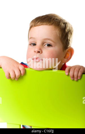 Boy looking over the back of a chair Stock Photo