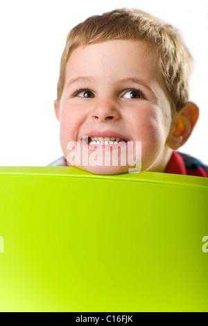 Grinning boy looking over the back of a chair Stock Photo