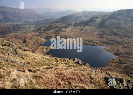 Easedale Tarn seen from the crag above. In the distance is Grasmere. English Lake District. Stock Photo