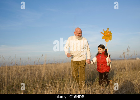 Girl with a pinwheel out on a walk with her grandfather Stock Photo