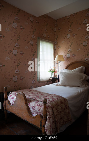 Single bed in 1830s Hudson Valley farmhouse bedroom with patterned wallpaper Stock Photo