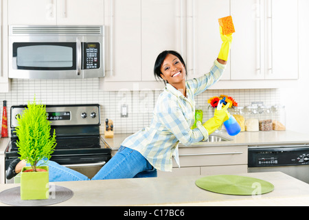 Smiling young black woman dancing and enjoying cleaning kitchen Stock Photo