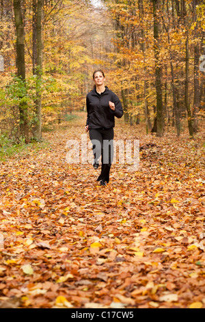 Young dark-haired woman during fitness training in an autumn forest Stock Photo