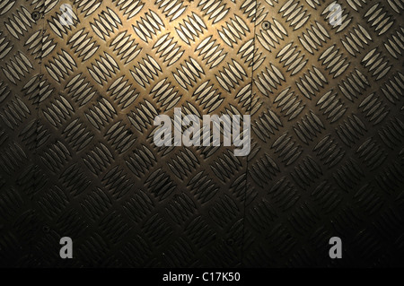 A spotlight's reflection glows on patterned aluminium flooring. Stock Photo