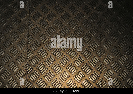 A spotlight's reflection glows on patterned aluminium flooring. Stock Photo