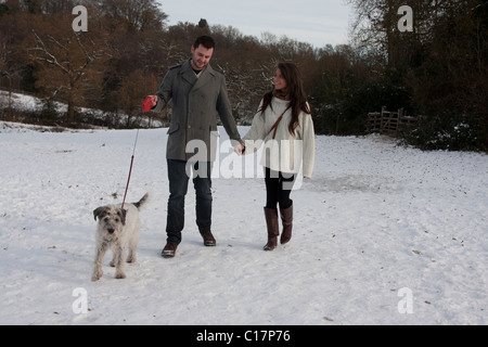 young couple walking dog in snow Stock Photo
