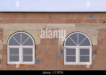 Raw brickwork with newly built in round arch windows, insulated glazing Stock Photo