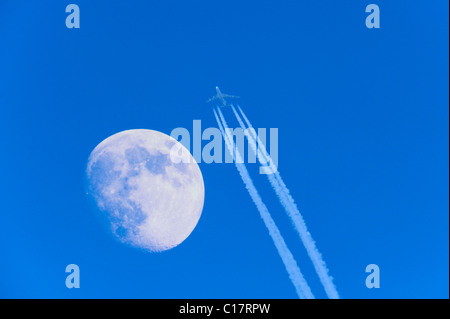 Passenger aircraft with jet trail and moon Stock Photo