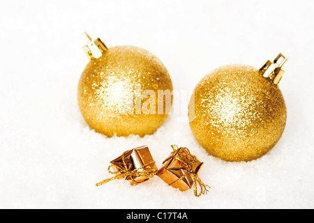Golden Christmas tree balls and wrapped gifts in snow Stock Photo
